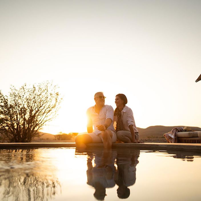 Guests at the pool during sunset at Desert Rhino Camp