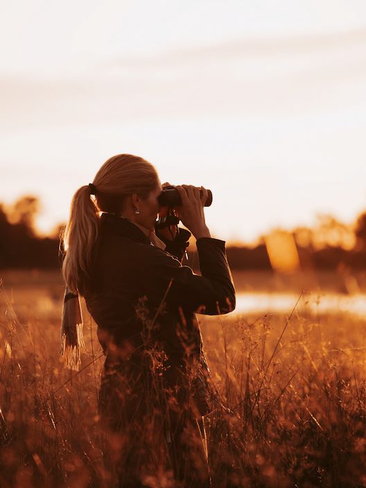 Vumbura Plains guest using binoculars to spot wildlife
